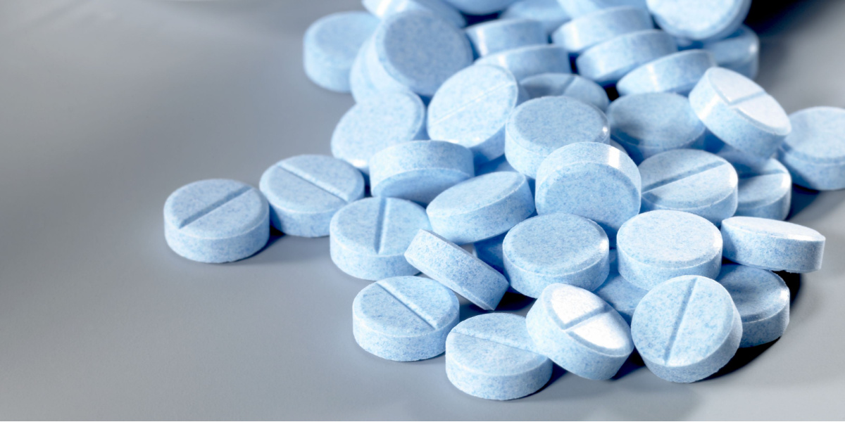 A pile of round, blue tablets with a scored line.
