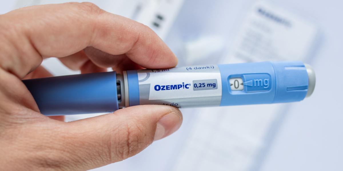 Hand holding a blue injection pen labeled
