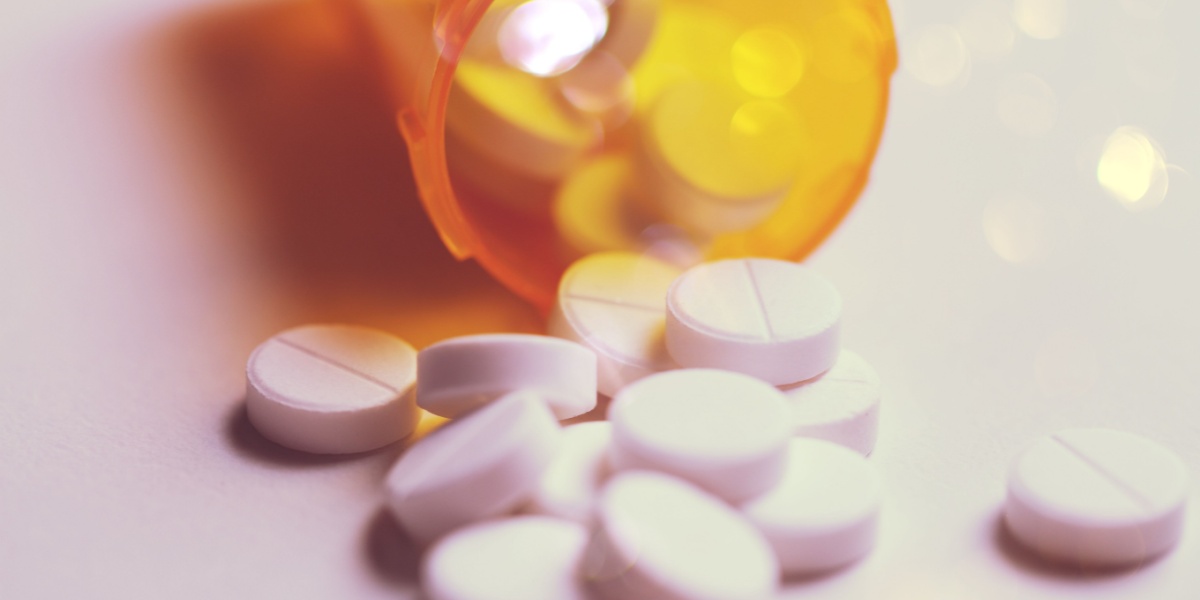 White pills spilling from an orange prescription bottle.