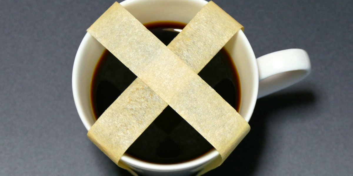 White cup filled with dark liquid, taped in an