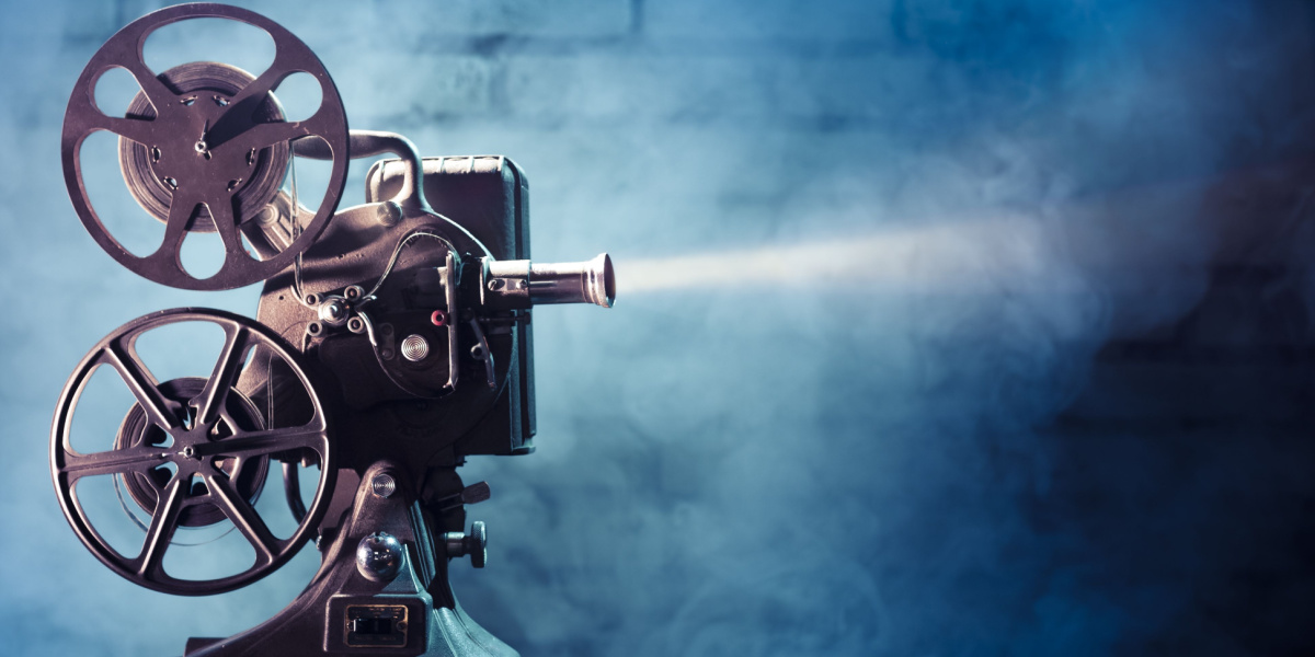 Old-fashioned film projector with reels emitting light in a smoky environment.