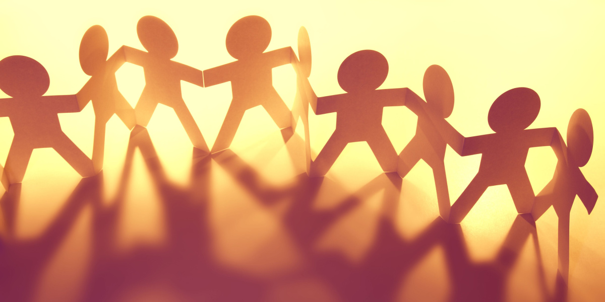 Paper chain cutouts of five human figures holding hands, with shadows.