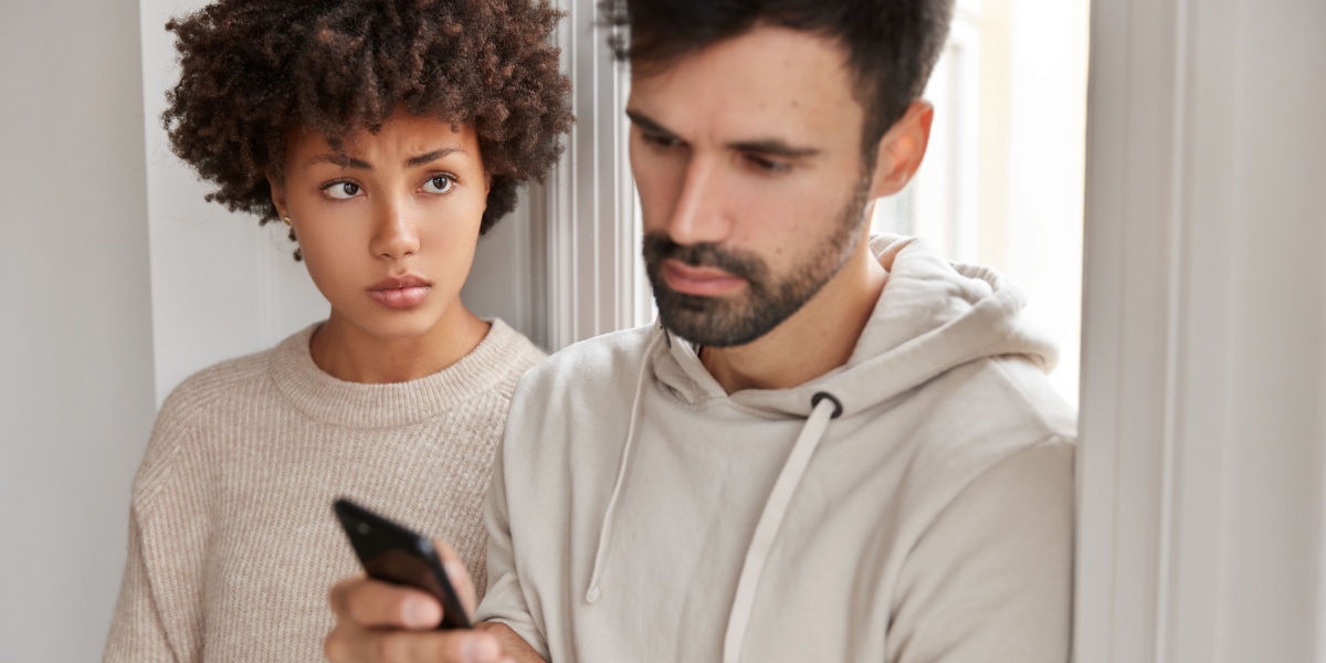 woman in light brown sweater looking over at a man in a brown hoodie worried over whether he has relapsed into addiction once again
