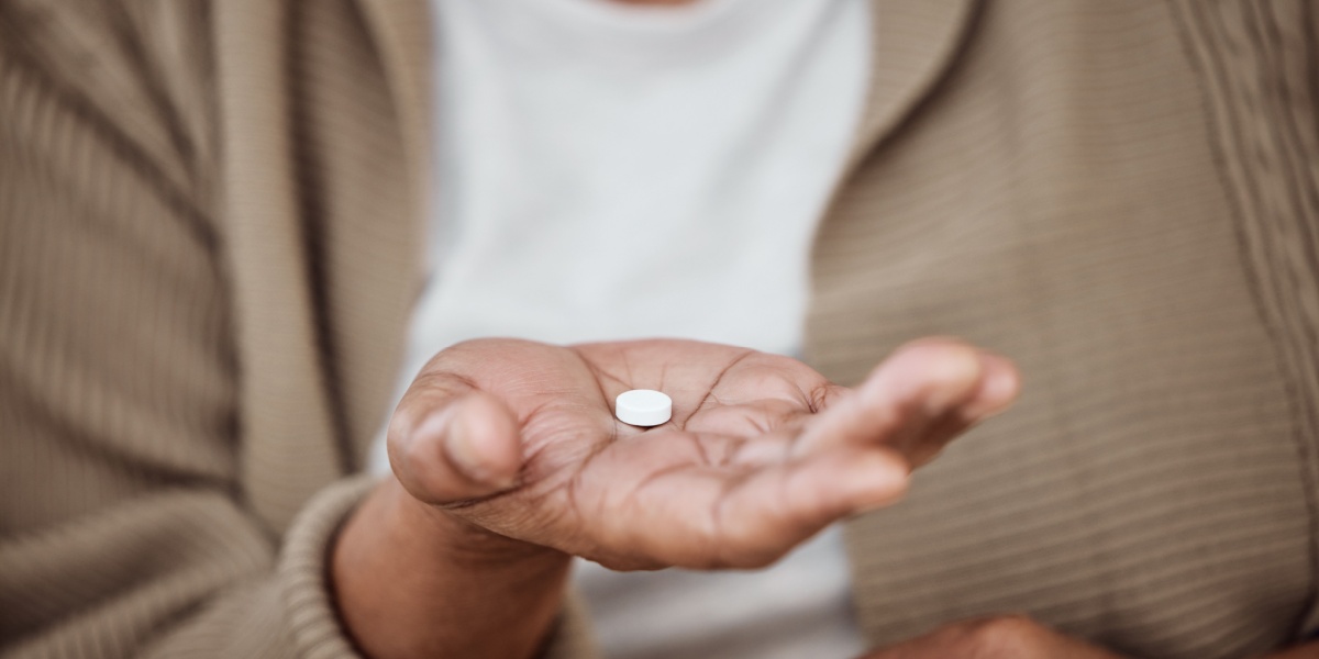 a black woman's hand in close up as she takes a trazodone pill for anxiety