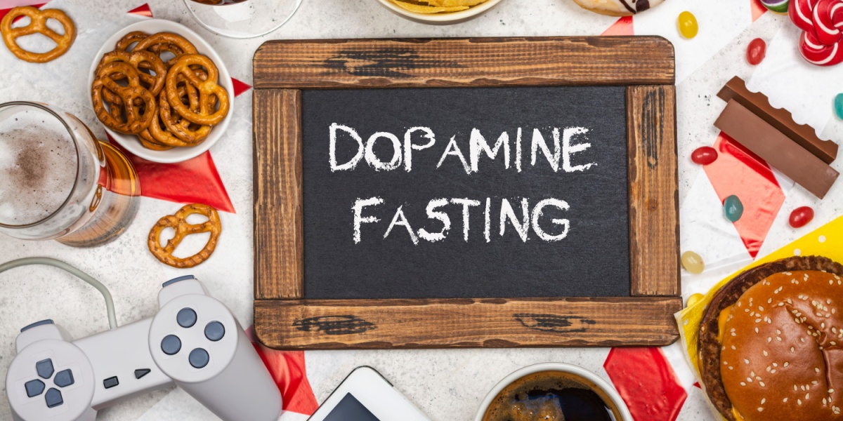 a photo of a sign with the words dopamine fasting, surrounded by various items that provide dopamine such as food and entertainment