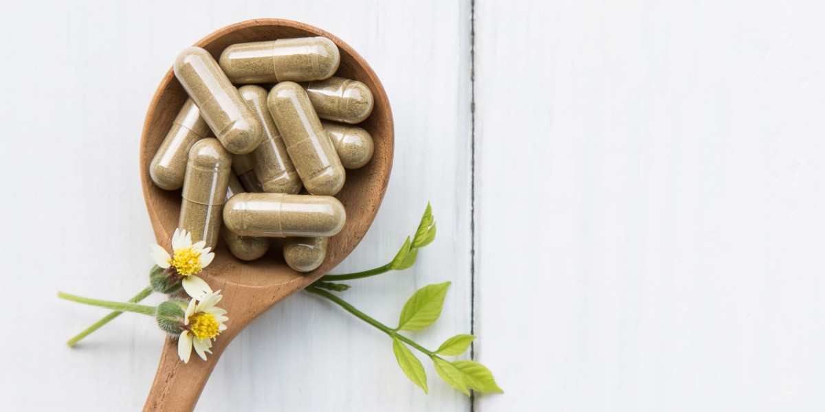 a close up photo of green pill ibogaine capsules on a large wooden spoon