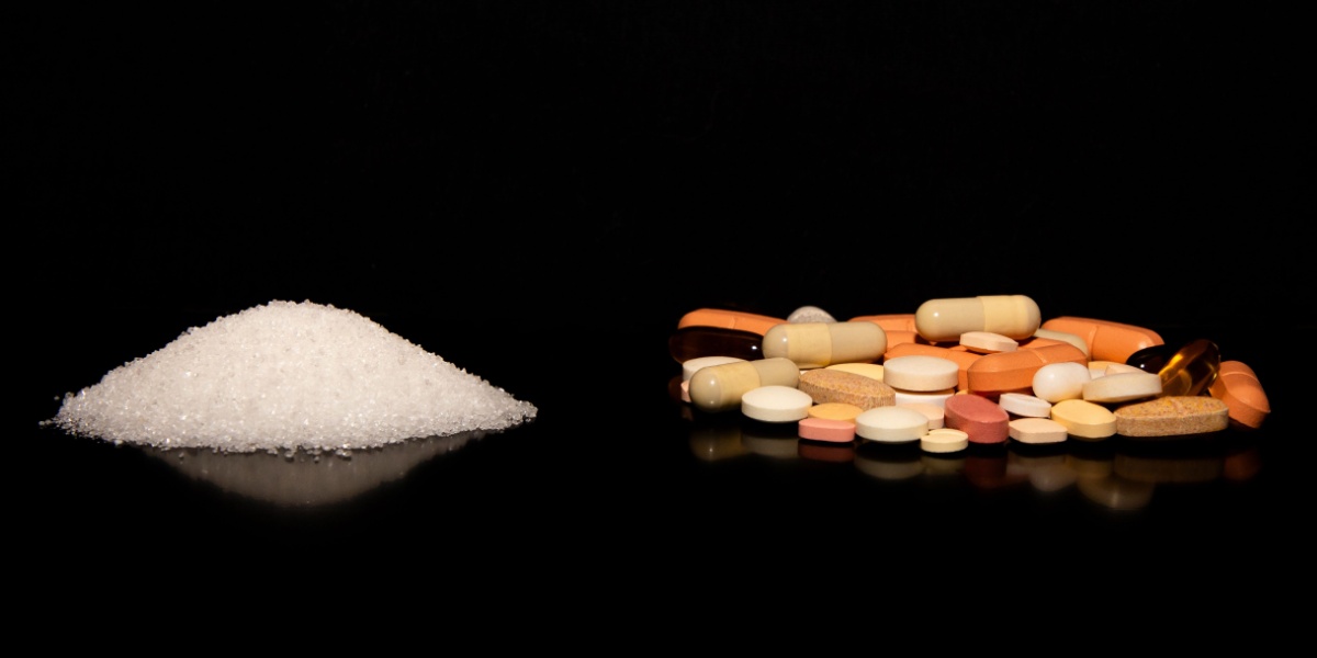 a photo of a clump of meth crystals on the left side and different forms of Adderall pills on the right side