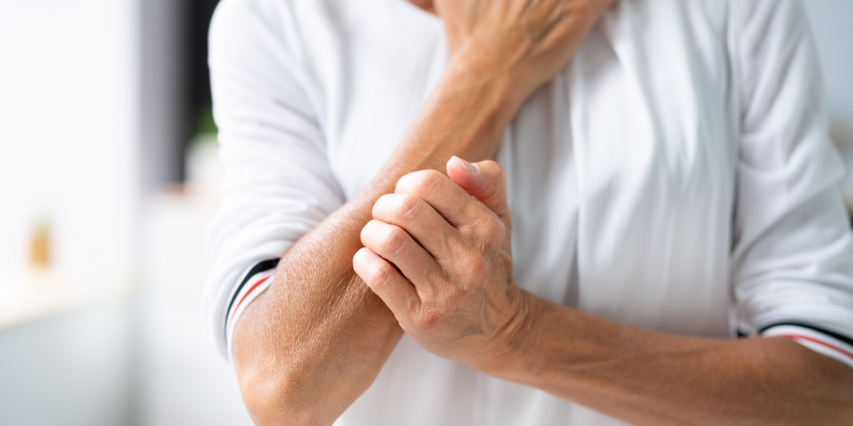 a close up photo of a man in white furiously scratching his arm due to meth mites hallucinations