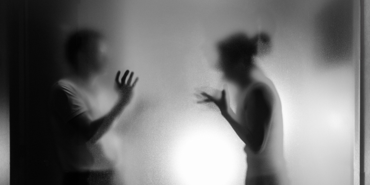 a black and white silhouette of a couple fighting over addiction behind a frosted glass