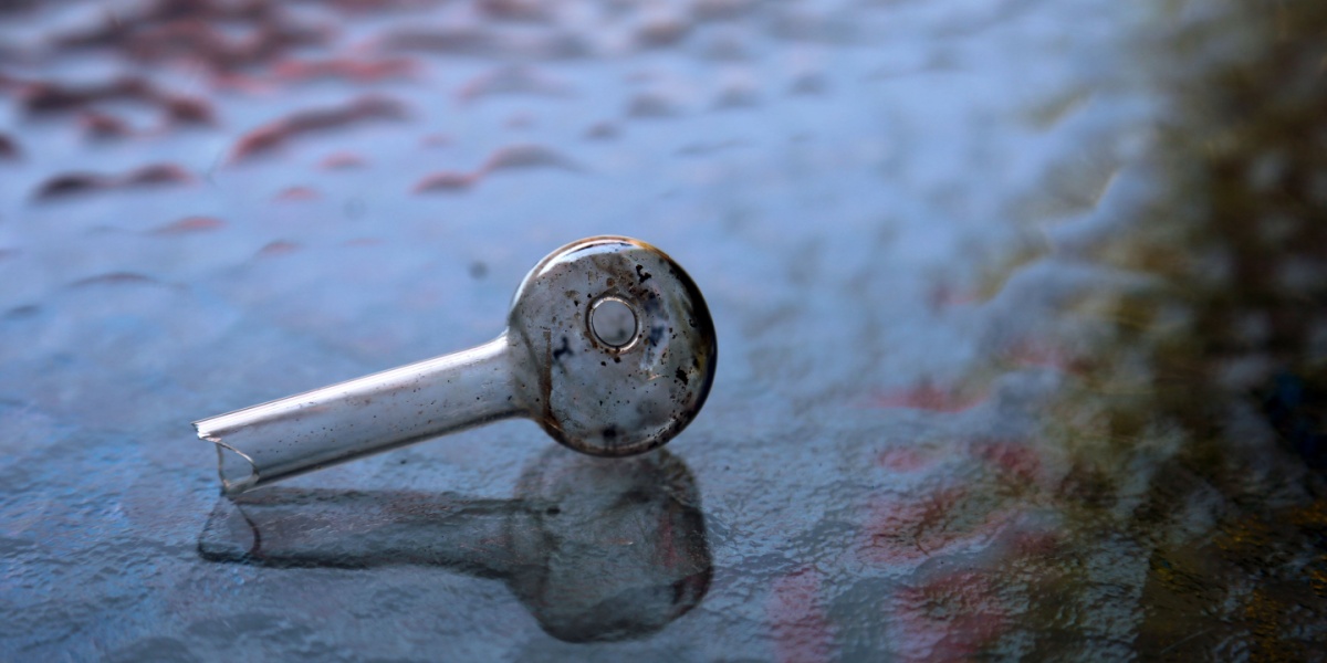 a photo of a glass meth pipe on a fluted glass texture background