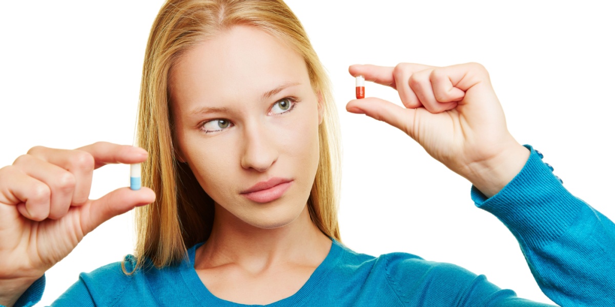 a photo of a blonde woman holding up a Concerta pill on one hand and an Adderall pill on the other