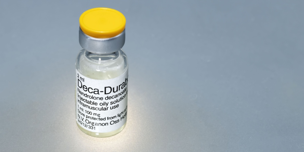 a photo of a nandrolone decanoate injection bottle over a gray background