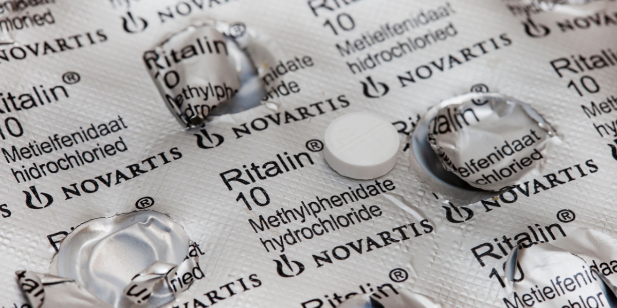 a close up photo of a Ritalin pill with the Ritalin blister pack in the background