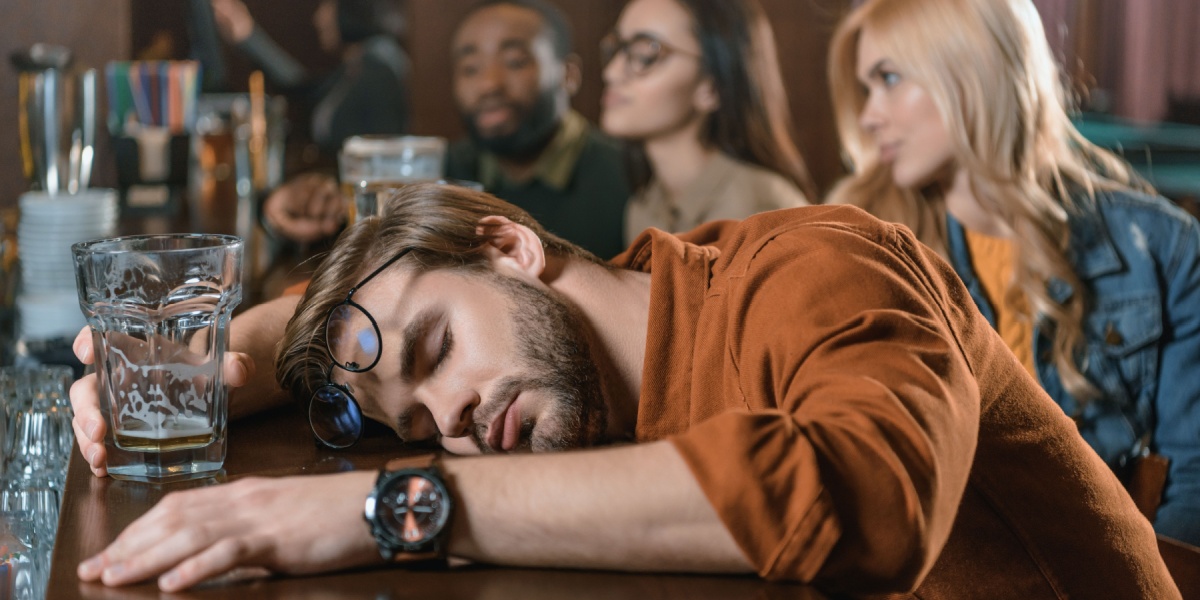 a photo of a Caucasian man with a watch passed out drunk in a bar and waiting to sober up