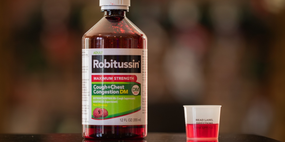 a photo of a Robitussin bottle and measuring cap beside it