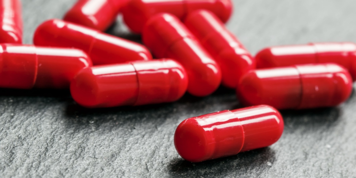a close up photo of red capsules or Zaza or gas station heroin in a dark gray textured background