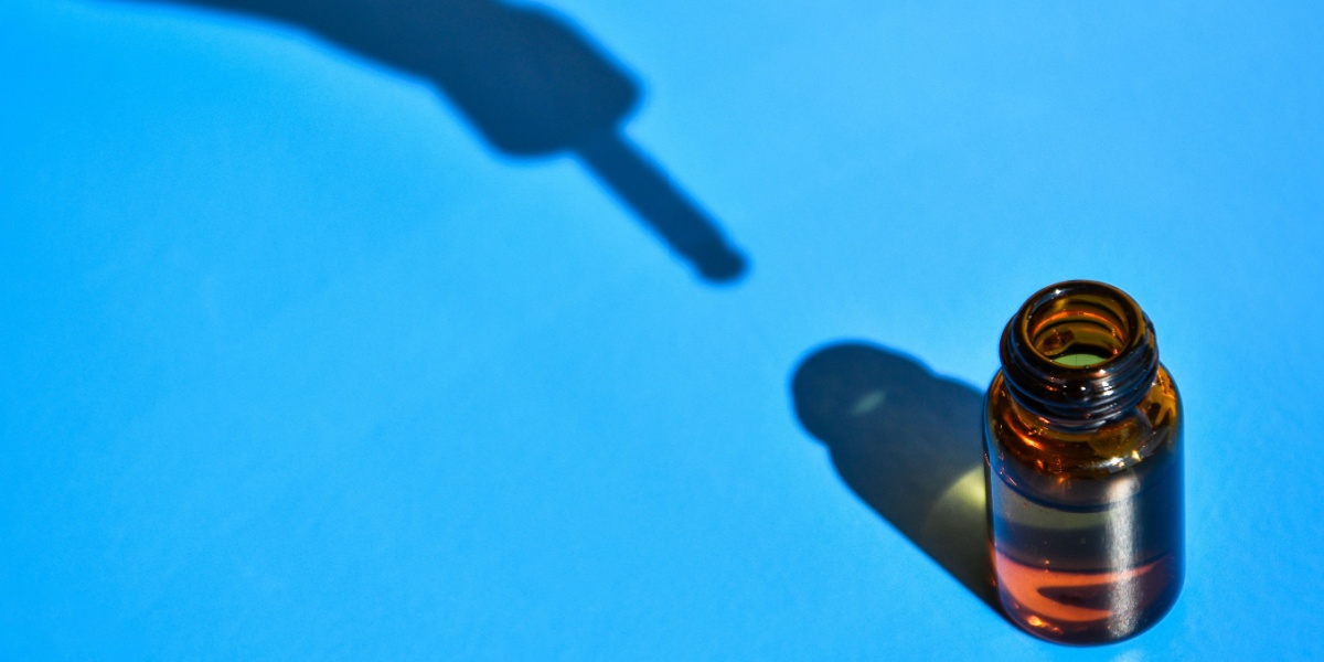 a close up photo of a bromantane vial with the shadow of a dropper against a blue background