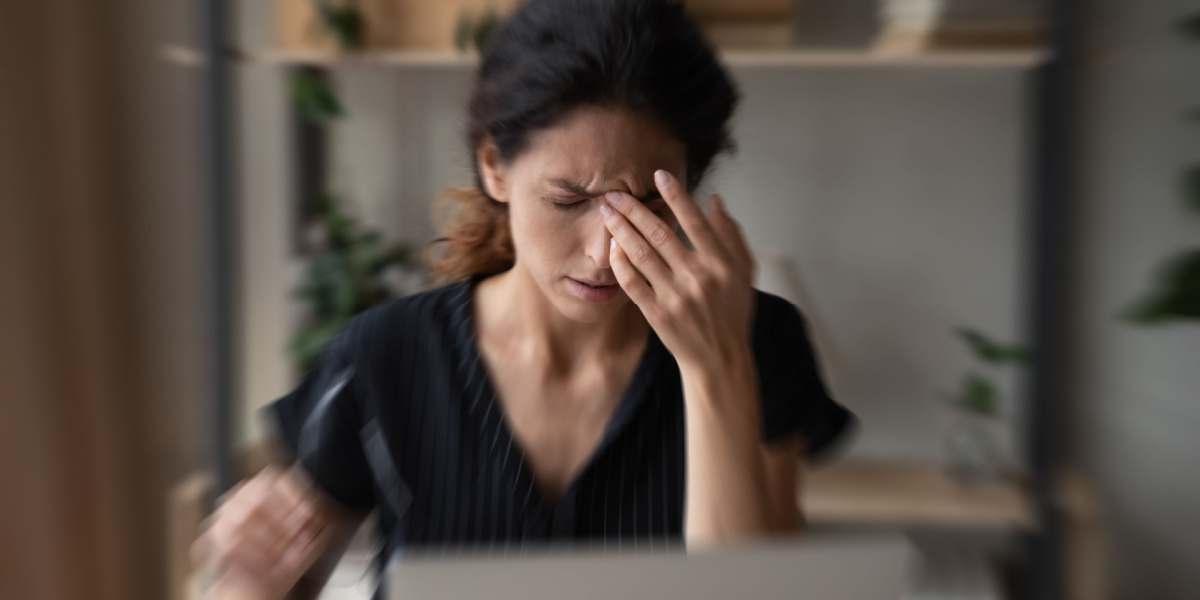 a close up photo of a woman with black hair experiencing blurry vision and dizziness because of hydroxyzine side effects