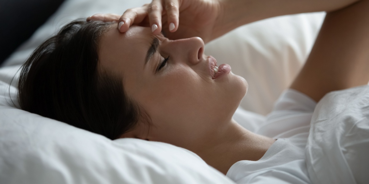 a close up photo of a Caucasian woman lying down in bed suffering from insomnia and dizziness due to amitriptyline withdrawal