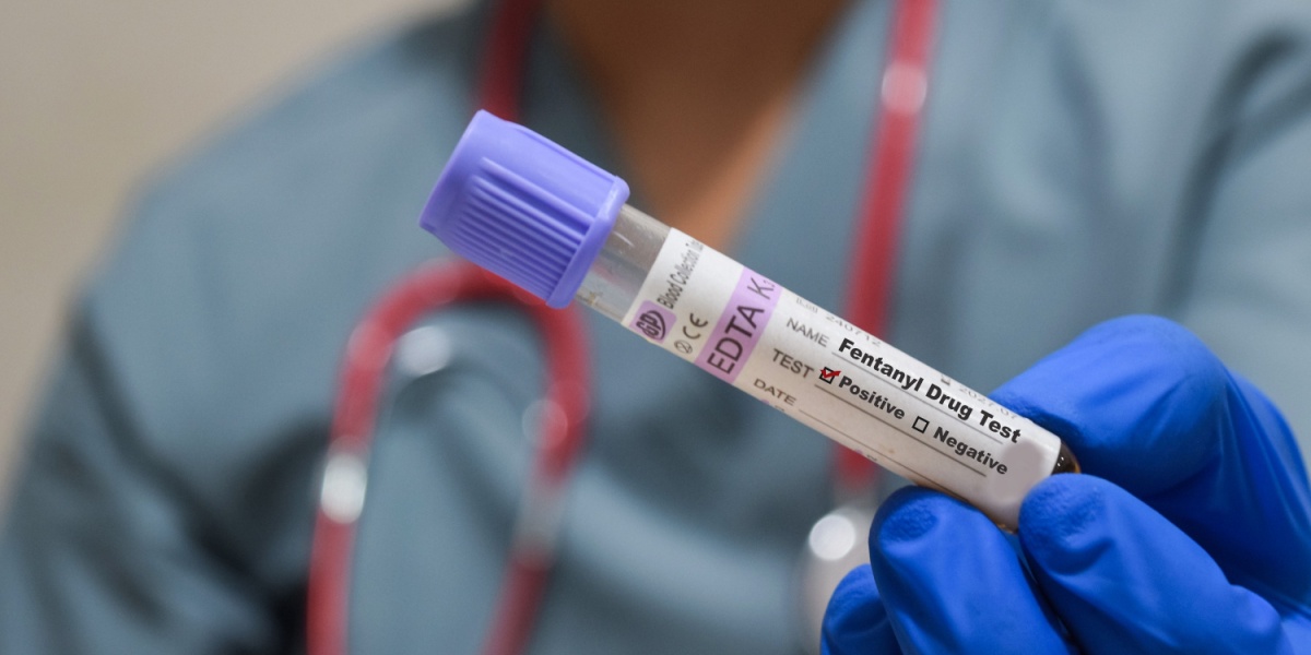 a close up photo of a blood sample in a test tube for an opioid drug test being held by a gloved hand
