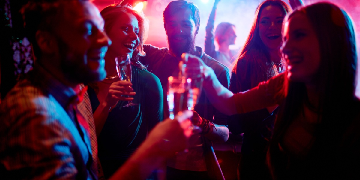 a photo of a group of people partying and getting to know each other in a bar while drinking alcohol