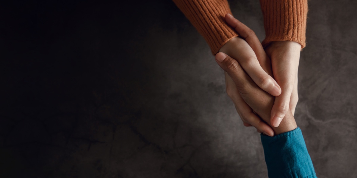 a bird's eye view photo of a pair of hands holding another person's hand in a symbol of helping them up