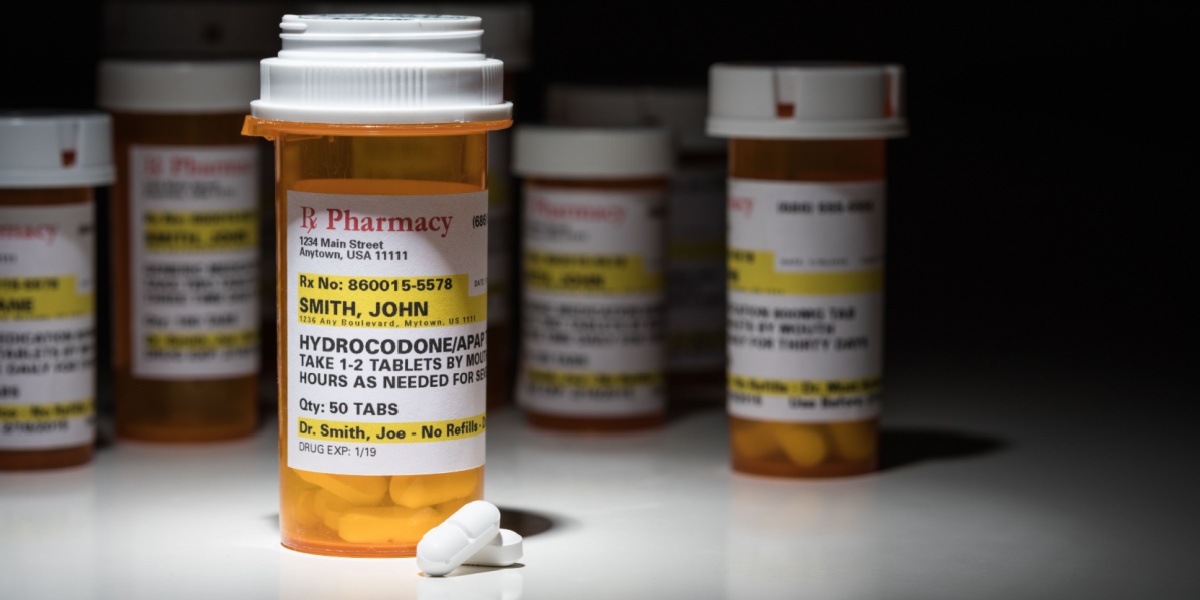 a close-up photo of a pill container containing opioids, with the medication label on the spotlight