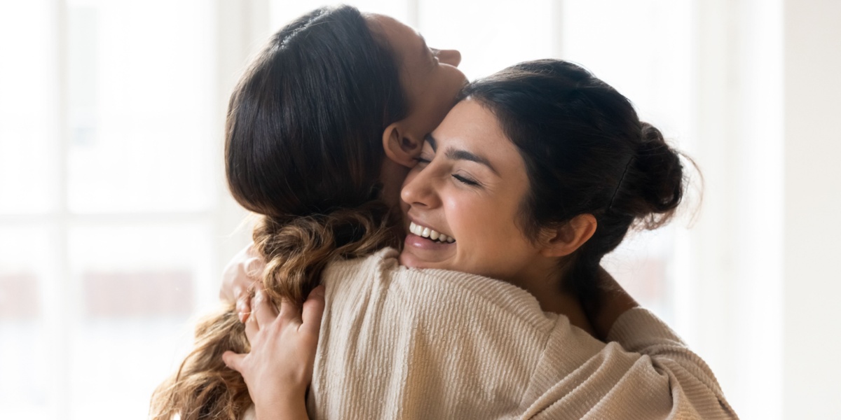a shoulder-level photo of two girls hugging each other for support and are feeling confident and happy