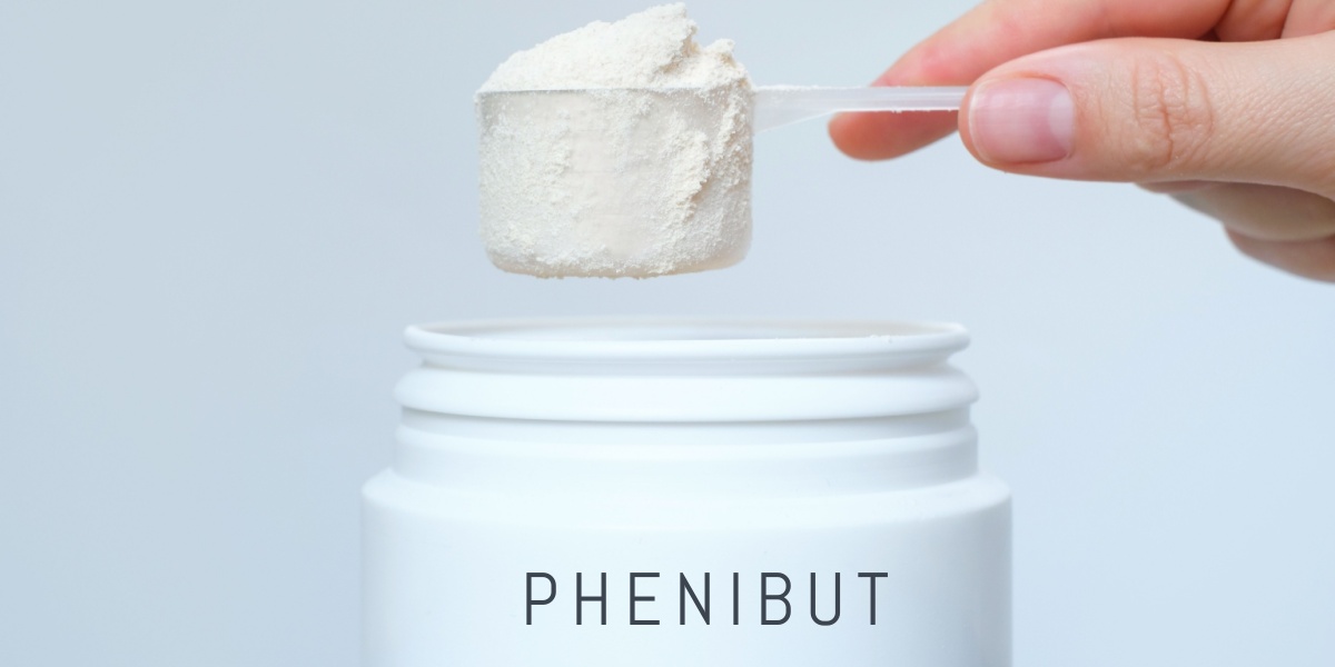 a close up photo of a hand holding a measuring cup full of phenibut powder