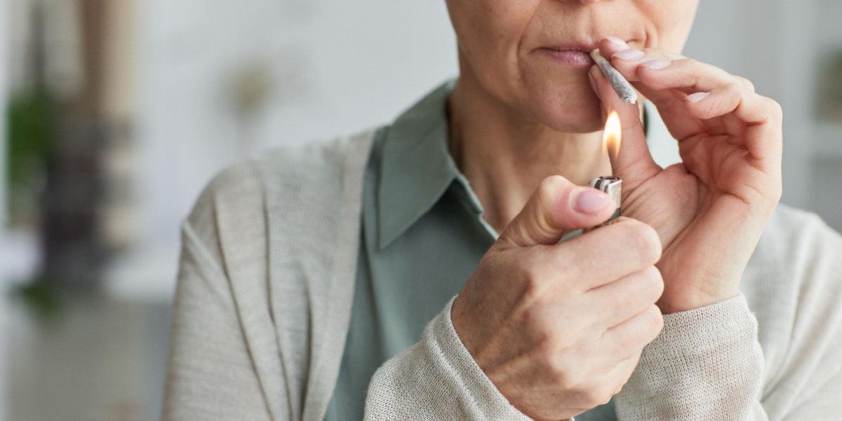 a close up photo of a thin person lighting up a cigarette