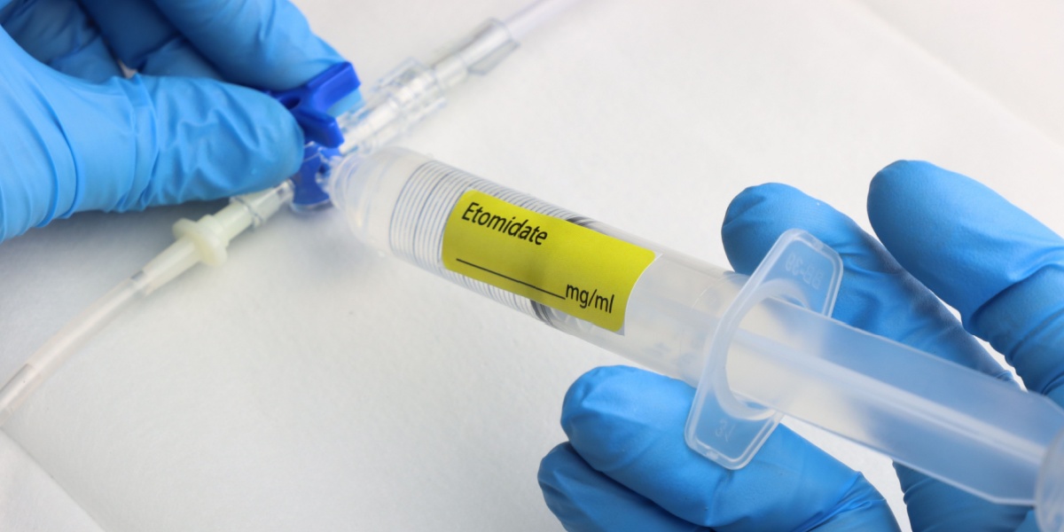 a close up photo of a pair of gloved hands holding a syringe full of etomidate