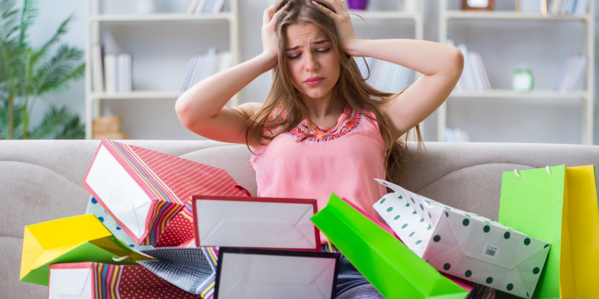a photo of a young Caucasian woman looking distressed while surrounded by multiple shopping bags