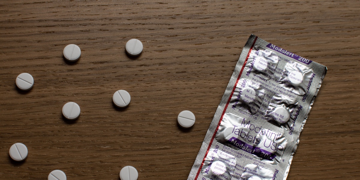 a photo of a modafinil blister pack and modafinil pills laid on a wooden table