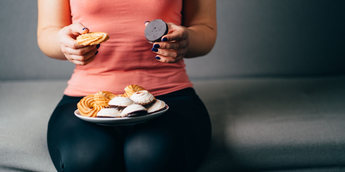 a lower body photo of a woman with a plate full of sweet food and desserts on her lap