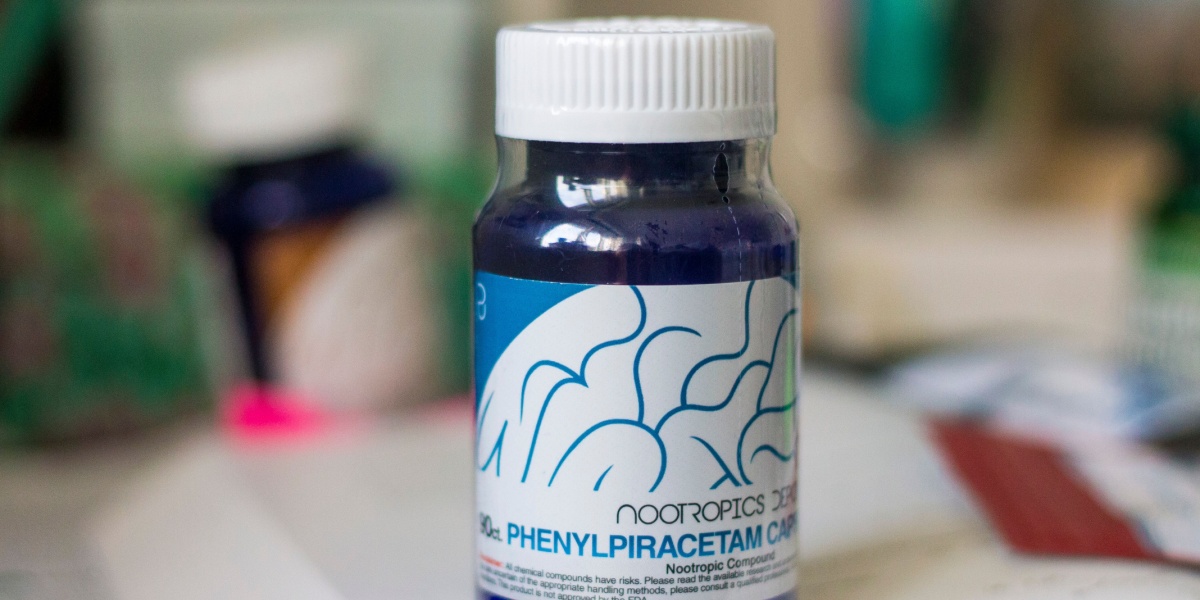 a close up photo of an unopened bottle of phenylpiracetam in the foregroundand the rest of the background is blurred