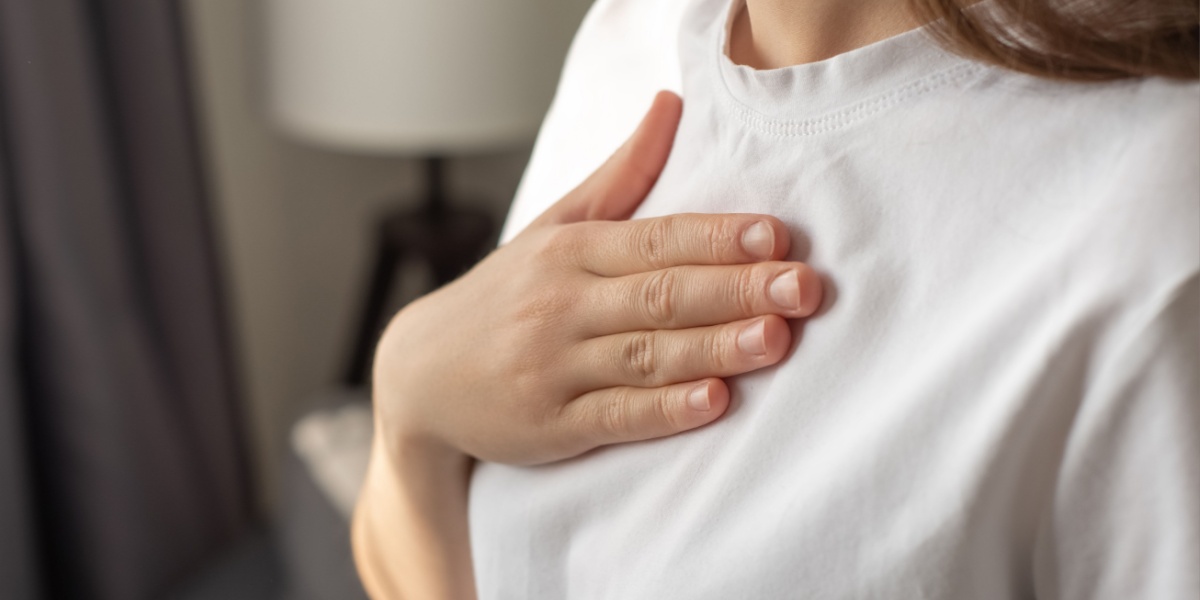 A close-up photo of a woman holding her chest because of irregular heartbeat due to fluoxetine (Prozac) overdose.