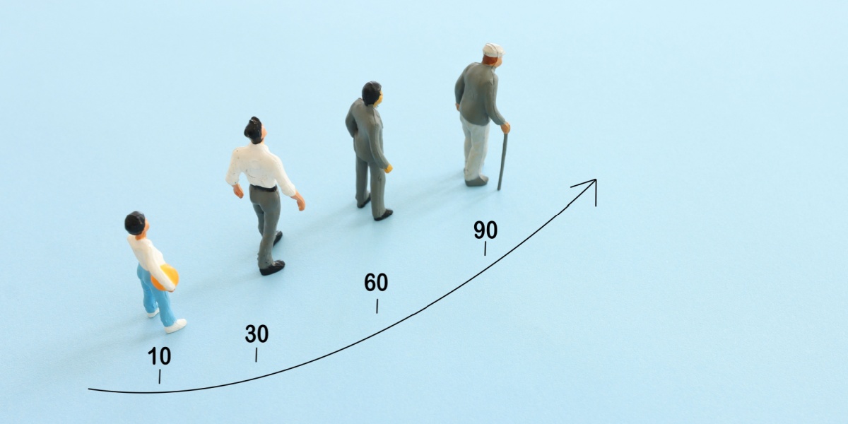 A top view photo of human figurines of different ages and an arrow drawn across the photo to show ascending ages