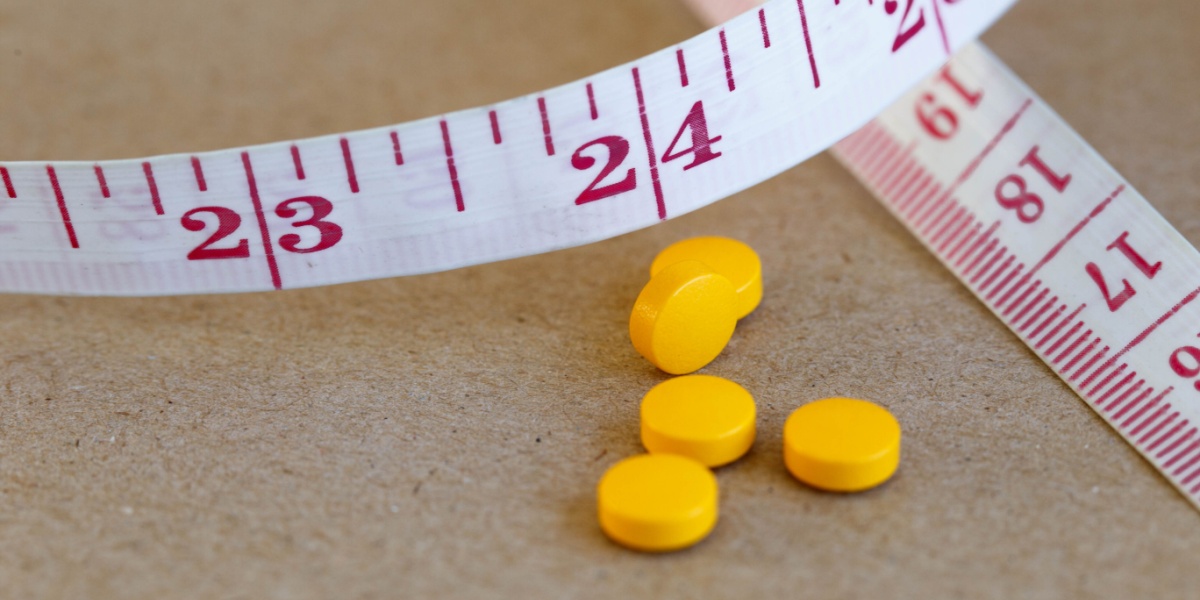 A close up photo of yellow circular amitriptyline pills with a measuring tape on the side