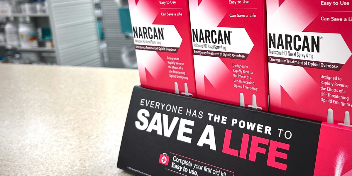 A photo of Naloxone or Narcan boxes with a sign 