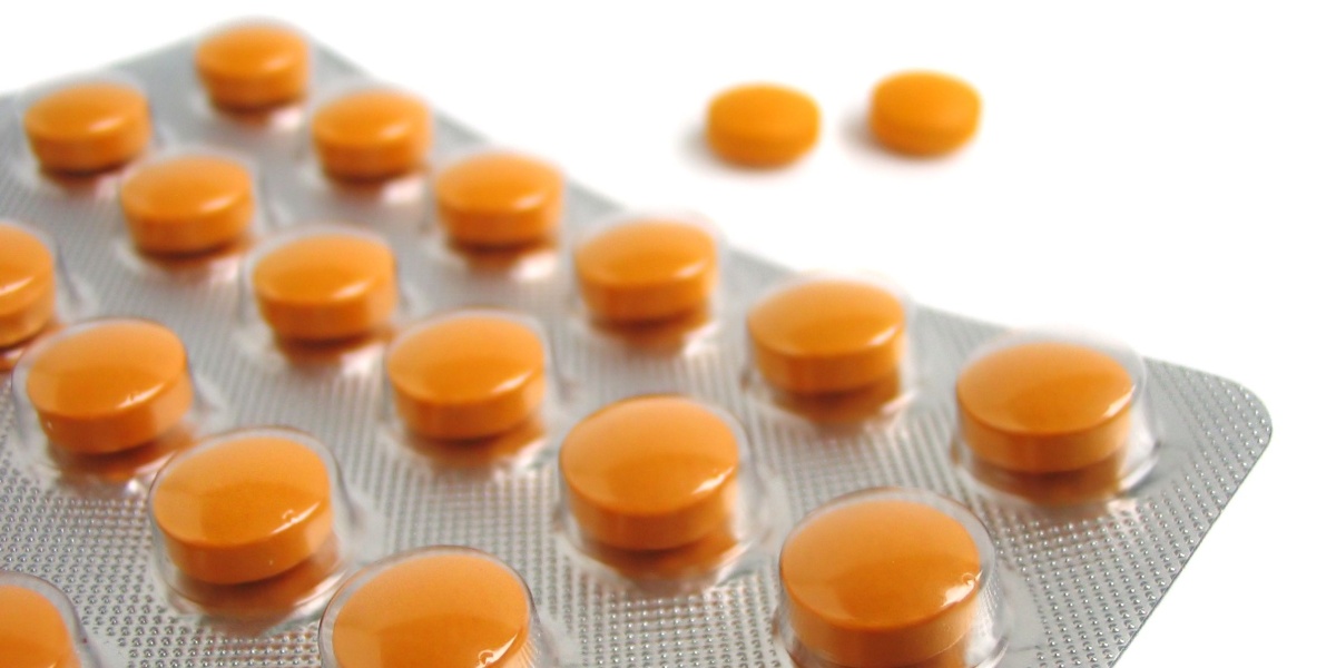 A close up of a blister pack full of Tapentadol pills and two tapentadol pills outside of the pack.