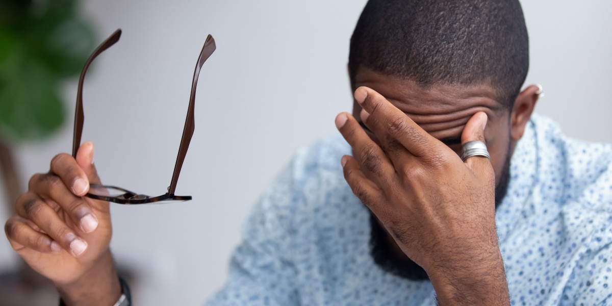 A close up of an African American man massaging his eyes due methocarbamol side effects like blurred vision and nausea